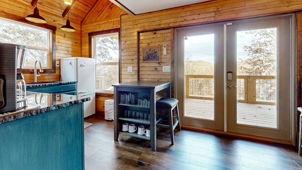L’intérieur d’une cabane en bois comprend un coin cuisine, une table à manger et une bibliothèque.