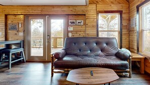Un intérieur de chalet chaleureux avec un canapé en cuir, une table basse en bois et un coin repas.
