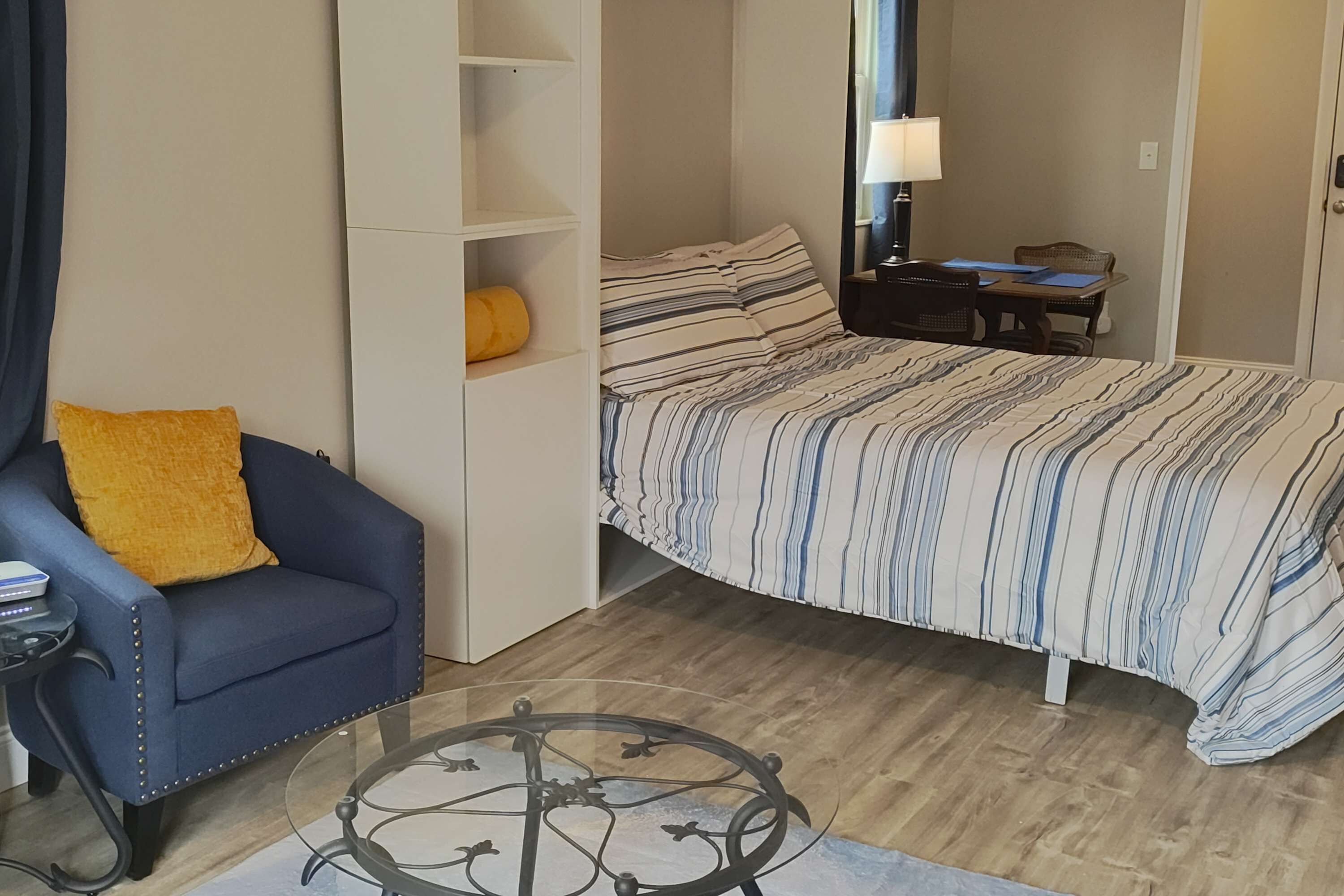 Ein gemütliches Schlafzimmer mit Bett, Sofa, kleinem Tisch und Bücherregal.