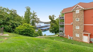 A two-story building with a stone facade and a red roof, overlooking a marina with boats and docks.