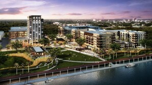 Een moderne stedelijke ontwikkeling met hoge gebouwen, een centraal park en een promenade aan het water.
