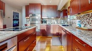 Una cocina moderna con armarios de madera, electrodomésticos de acero inoxidable y un salpicadero de azulejos.