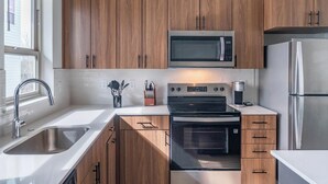Une cuisine moderne avec des meubles en bois, des appareils électroménagers en acier inoxydable et une fenêtre qui laisse entrer la lumière naturelle.