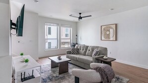 Un salon moderne avec un canapé, une table basse et un téléviseur fixé au mur.