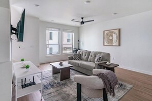 A modern living room with a sofa, coffee table, and a TV mounted on the wall. - Landing | Spectacular 2BD, Clubhouse, Gym (Billings)