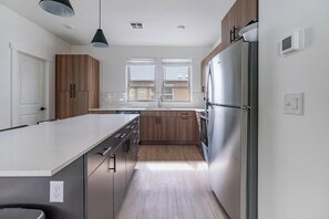 A modern kitchen with wooden cabinets, a stainless steel refrigerator, and a large island. - Landing | Beautiful 2BD, Clubhouse, Gym (Billings)