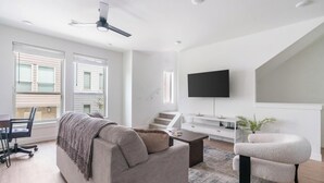 Een moderne woonkamer met een bank, salontafel, televisie en trap.