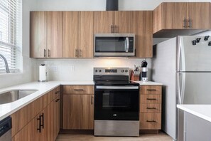 A modern kitchen with wooden cabinets, a stainless steel refrigerator, a microwave, and an oven. - Landing | Modern 2BD, Gym, Clubhouse (Billings)