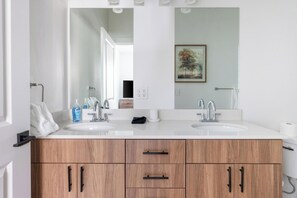 A bathroom with two sinks, a large mirror, and wooden cabinets. - Landing | Chic 2BD, Gym, Clubhouse (Billings)