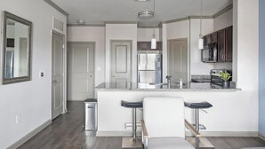 Una cocina moderna con una isla central, electrodomésticos de acero inoxidable y un taburete de bar.