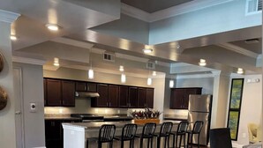 Una cocina amplia con armarios de madera oscura, una isla central con taburetes de bar y un refrigerador grande.