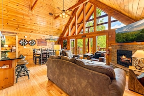A spacious wooden cabin with a large living area featuring a fireplace, a dining area, and a kitchen with a bar. - Luxury Mtn Retreat W Breathtaking Views, Sleeps 14 (Gatlinburg)
