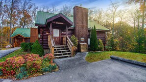 A rustic log cabin with a green roof, a front porch, and a staircase leading to the entrance. - Gatlinburg Cabin W Hot Tub・Jacuzzi Tub・Seelsp 4 (Gatlinburg)