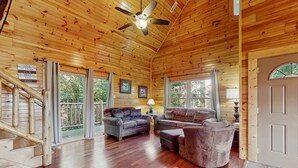 A wooden cabin interior with a staircase, two sofas, a lamp, and a ceiling fan. - Centrally Located Cabin, Sleeps 6・Pool Table・Views (Gatlinburg)