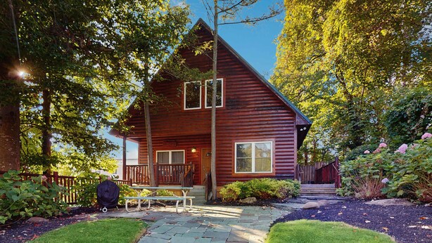 A wooden cabin with a porch, surrounded by lush greenery and a stone pathway. - Centrally Located Cabin, Sleeps 6・Pool Table・Views (Gatlinburg)