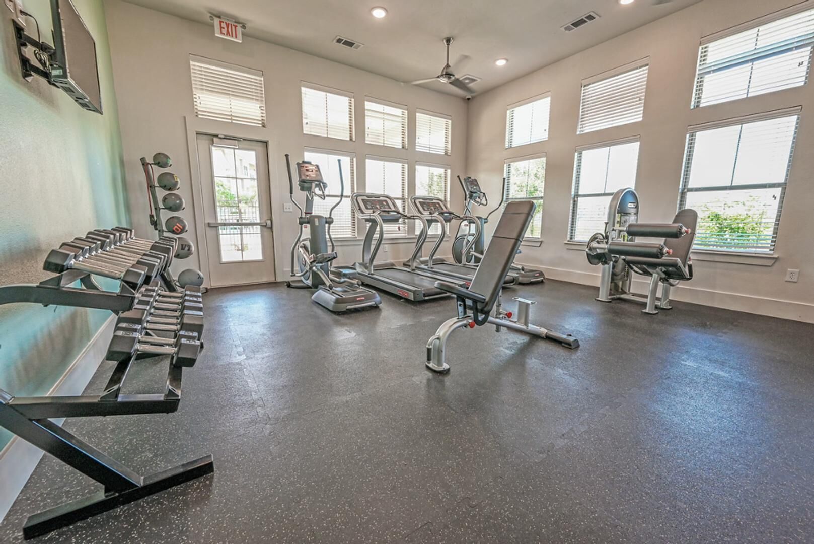 Une salle de sport équipée de tapis de course, d’appareils de musculation et d’haltères.