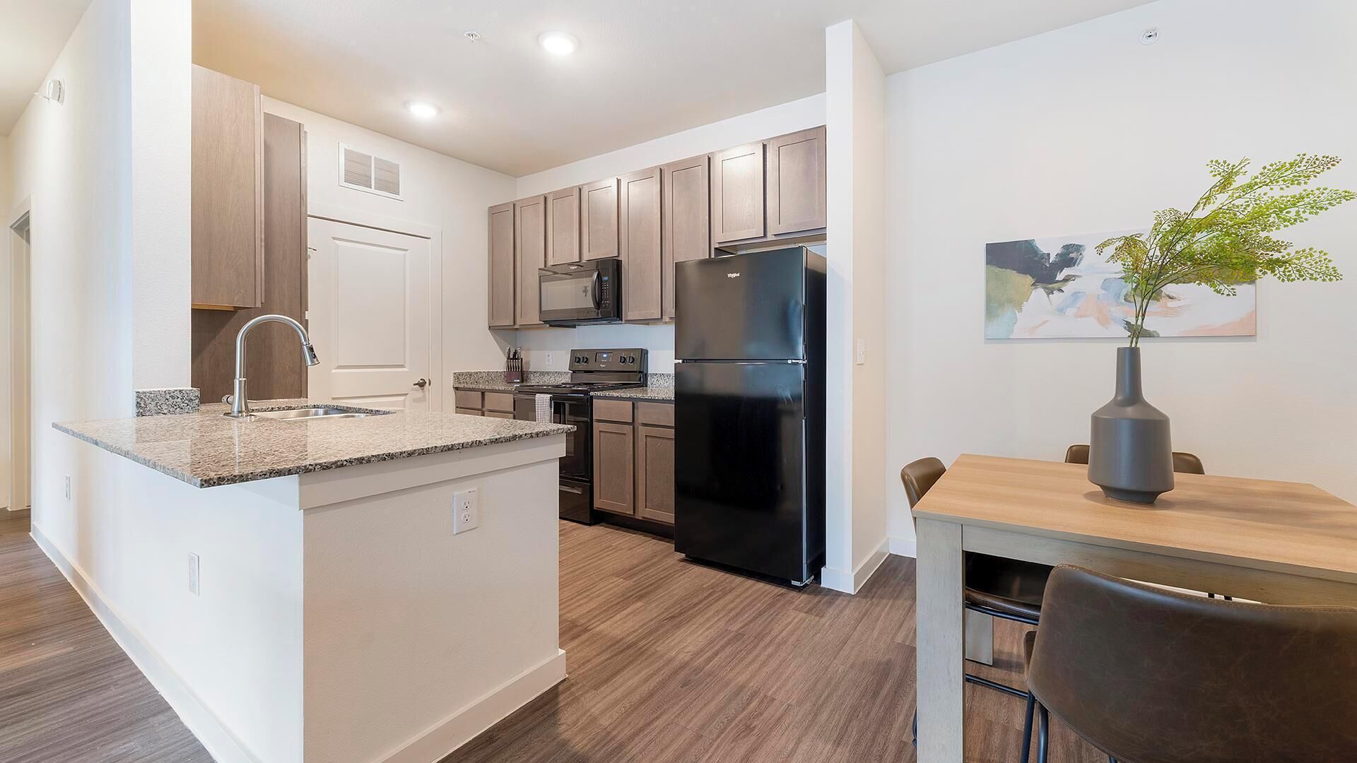 A modern kitchen with a built-in island, stainless steel appliances, and a dining area with a table and chairs.