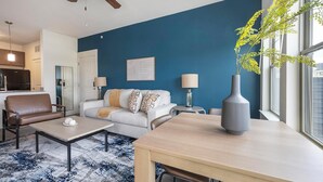 Een moderne woonkamer met een blauwe accentmuur, een bank, een salontafel en een eettafel.