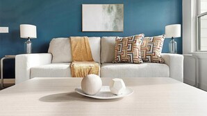 Una sala de estar moderna con un sofá, almohadones estampados, un cuenco decorativo y dos lámparas.
