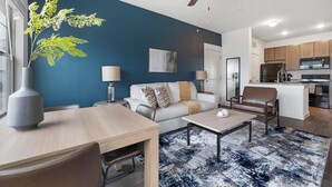 A modern living room with a sofa, coffee table, and dining table. There is a kitchen area with cabinets and appliances. - Landing | Spectacular 1BD, Gym, Pool (Lockhart)