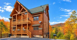 A log cabin with a balcony, a stone foundation, and a mountain backdrop. - Family Friendly Woodland Cabin・Hot Tub・Games・View (Pigeon Forge)