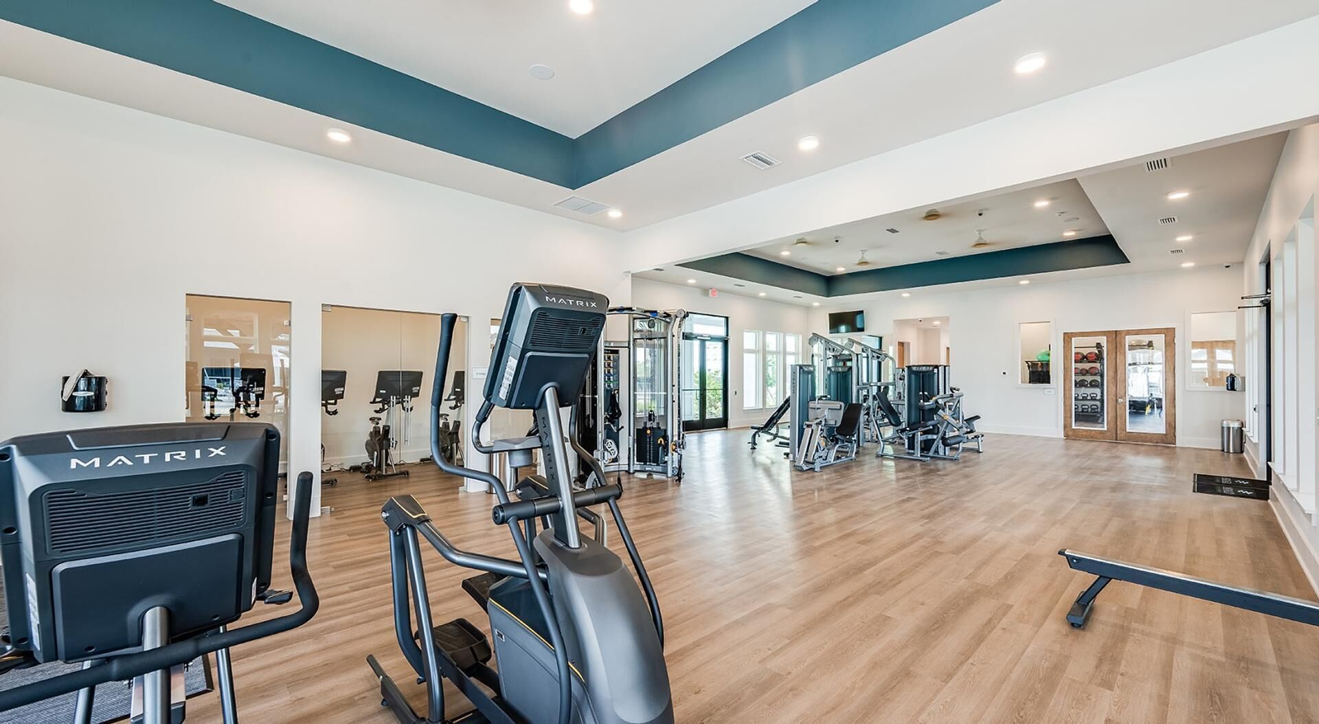 Et rummeligt fitnesscenter med forskellig træningsudstyr, herunder løbebånd og vægtmaskiner.