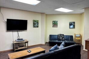 Ein Wohnzimmer mit Flachbildfernseher, einer Couch, einem Couchtisch und zwei Bildern an der Wand.
