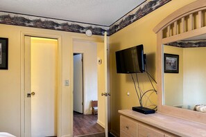 Ein Hotelzimmer mit einem Holznächtigungsschrank, einem angebrachten Fernseher und einer Tür zu einem weiteren Raum.