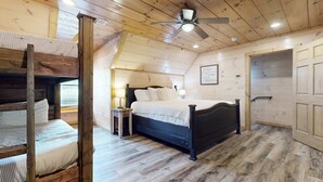 A cozy bedroom with a bunk bed, a single bed, wooden flooring, a ceiling fan, and a door. - 4BR Cabin Near Dollywood・2 Hot Tubs・Grill・Pool (Pigeon Forge)