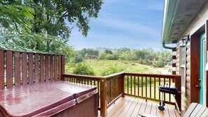 A wooden deck with a hot tub, a grill, and a chair. - 4BR Cabin Near Dollywood・2 Hot Tubs・Grill・Pool (Pigeon Forge)