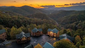 A lodge with multiple buildings, a parking area, and a mountainous backdrop. - Large Group Cabin for 60, Two Hot Tubs , Theater and Game Room, Resort Pool (Pigeon Forge)