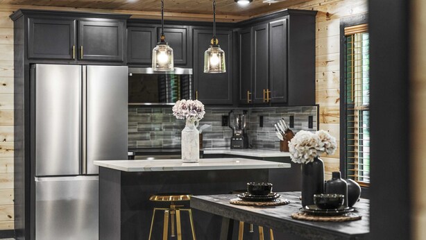 A modern kitchen with dark cabinetry, stainless steel appliances, and a central island with stools.