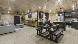 A modern log cabin interior with a kitchen, dining area, and living room.