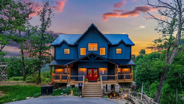 A large, two-story house with a steep gable roof, a front porch, and a red door. - Spacious Scenic Cabin, Sleep 12, Games, Hot Tub, View (Sevierville)