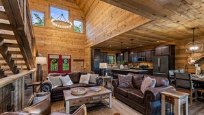 A spacious living area with leather sofas, a coffee table, and a wooden staircase. - Spacious Scenic Cabin, Sleep 12, Games, Hot Tub, View (Sevierville)