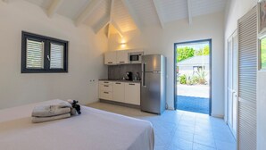 Ein Schlafzimmer mit Bett, einer kleinen Küchenzeile und einer Tür zum Patio.