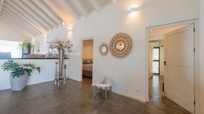 A spacious living area with a high ceiling, a large window, and a kitchen area visible in the background. - Villa Kokolishi - Coral Estate Resort (Sint Willibrordus)