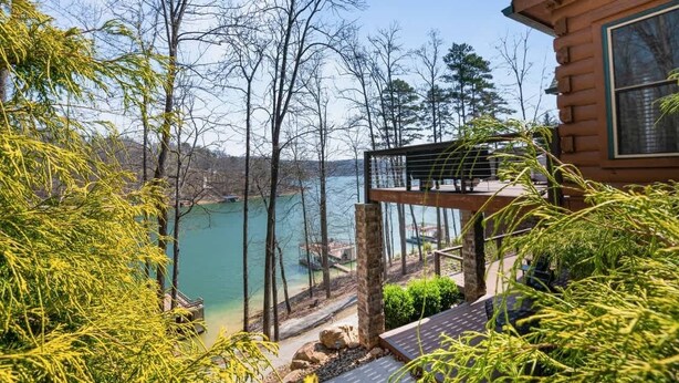 A cabin with a balcony overlooking a lake, surrounded by trees. - Family-Friendly Big Creek Getaway・Hot Tub・Firepit (LaFollette)
