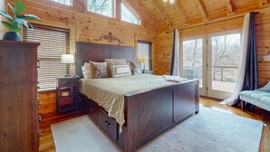 A wooden cabin bedroom with a large bed, a nightstand, a dresser, and a ceiling fan. - Family-Friendly Big Creek Getaway・Hot Tub・Firepit (LaFollette)