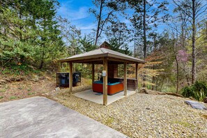 Ein Pavillon mit Whirlpool, umgeben von Kieswegen und Bäumen.