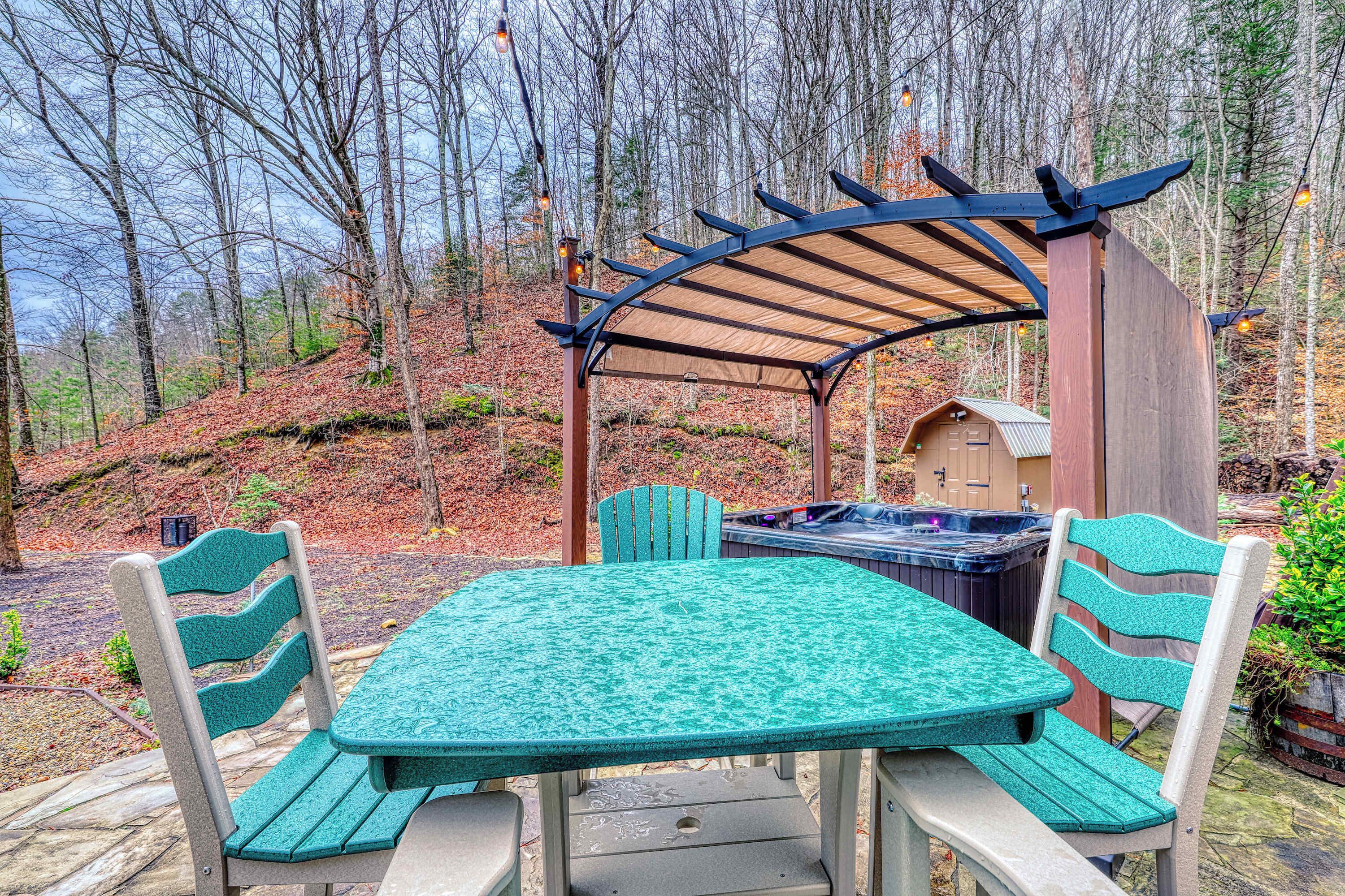 An outdoor patio with a table and chairs, a hot tub, and a wooden structure.
