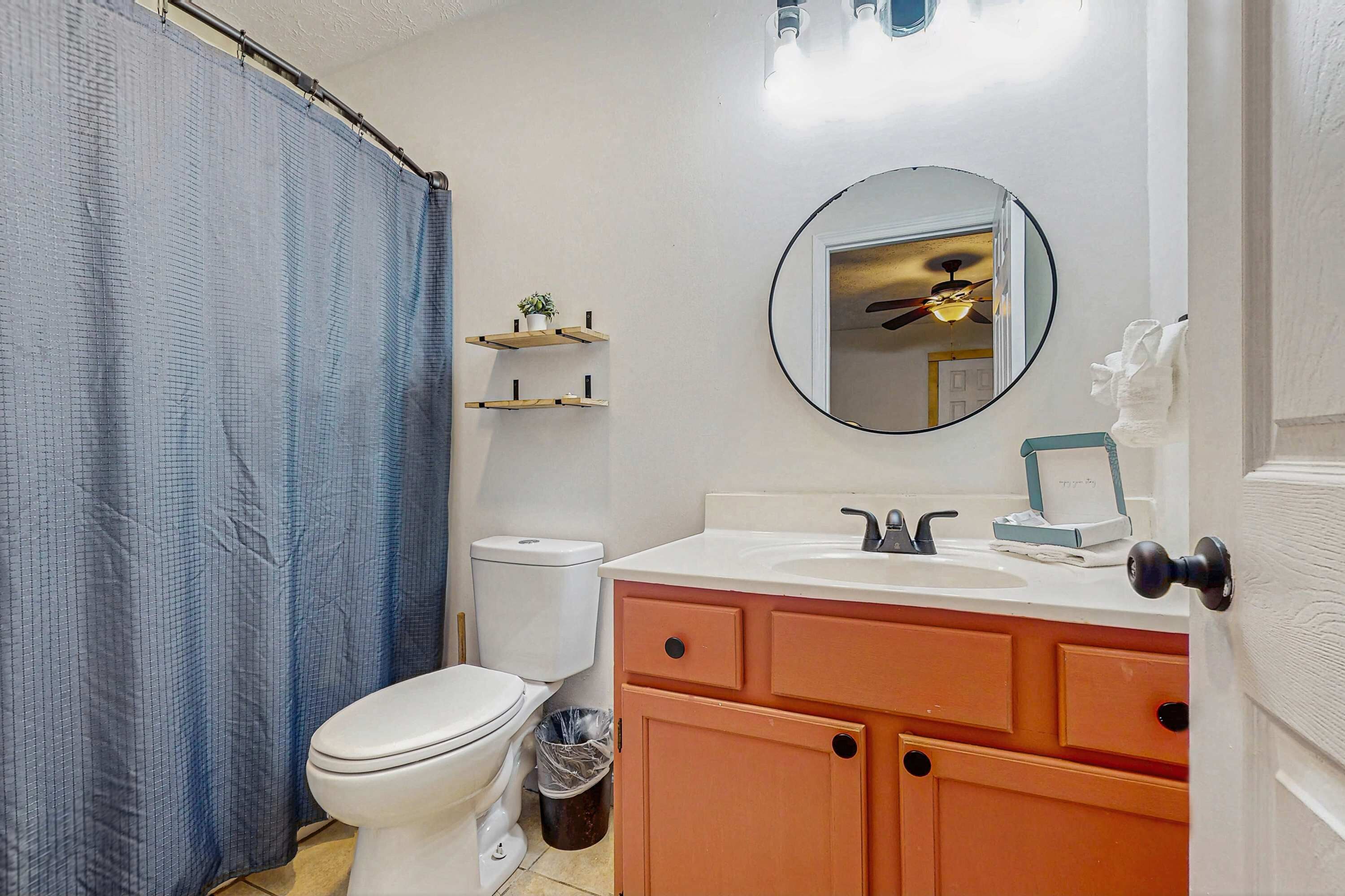 Un baño con inodoro, lavamanos, espejo y cortina de ducha.
