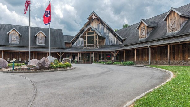 Eine rustikale Lodge mit einem markanten Hauptgebäude, einem überdachten Außenbereich und einer geschwungenen Auffahrt.