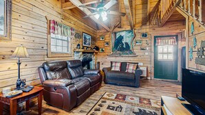 Ein gemütliches Cabin-Interieur mit einer Ledersofa, einem Fernseher und einem Deckenventilator.