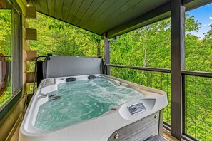 A hot tub on a balcony with a view of lush greenery. - The Treehouse, Sleep 12・Hot Tub・Firepit・Game Room (Sevierville)