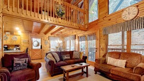 A cozy cabin interior with a wooden interior, a balcony with a hanging wreath, and a dining area with a sign reading "Happy". - 3.5 Mi to DT Pigeon Forge・Dog Ok! Getaway・Hot Tub (Pigeon Forge)