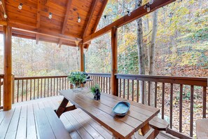 Une terrasse en bois avec une table de pique-nique, des plantes en pot et un plateau en métal.