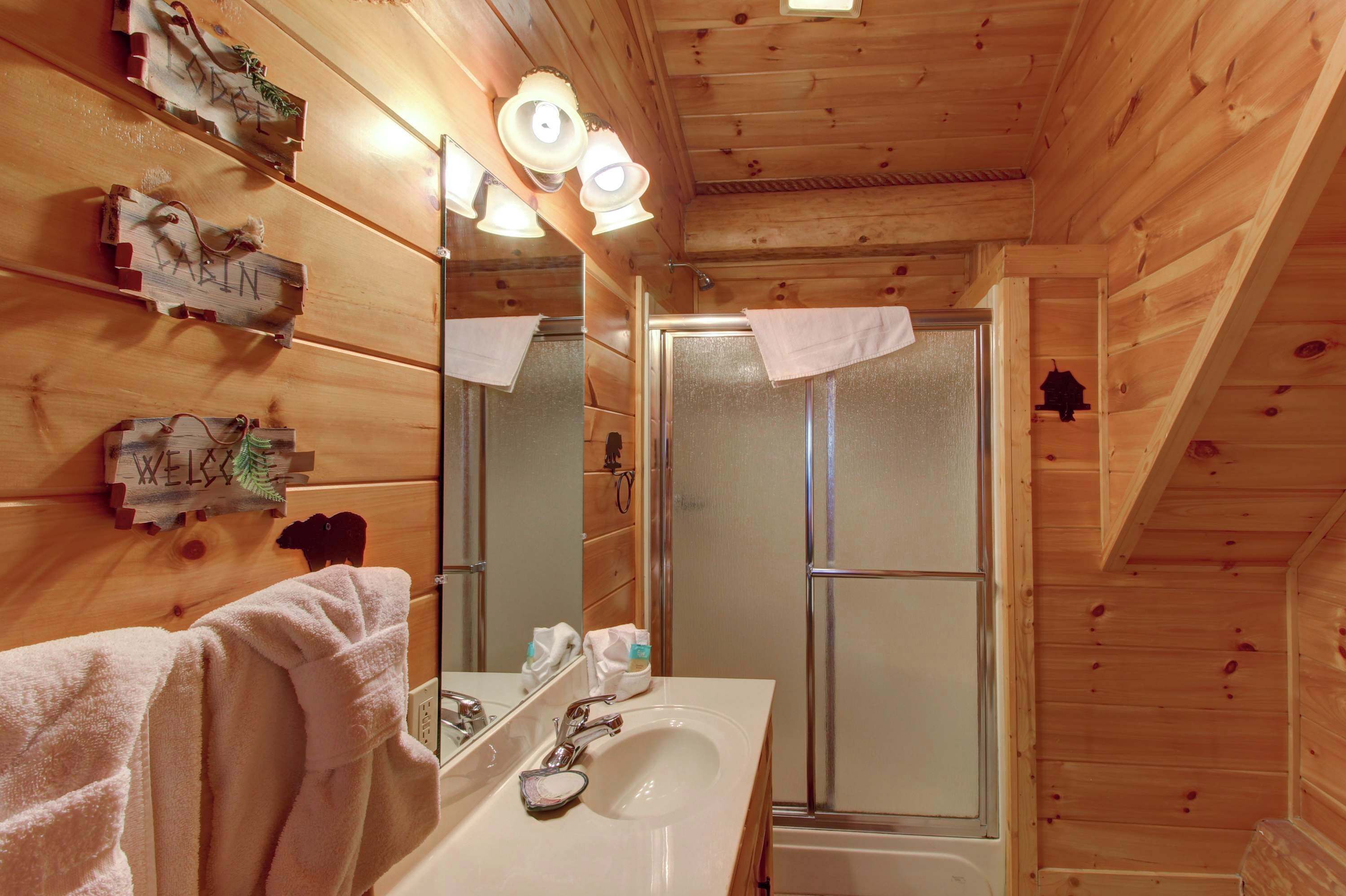Ein Badezimmer einer Holzhütte mit Waschbecken, Spiegel und Dusche.