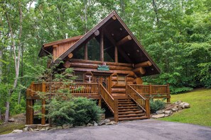 A log cabin with a wooden staircase leading to a deck, surrounded by trees. - Pet Friendly Near Dollywood Cabin・Hot tub・Views (Sevierville)