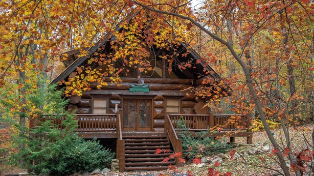 A log cabin with a wooden staircase leading to a front door, surrounded by autumn foliage. - Pet Friendly Near Dollywood Cabin・Hot tub・Views (Sevierville)